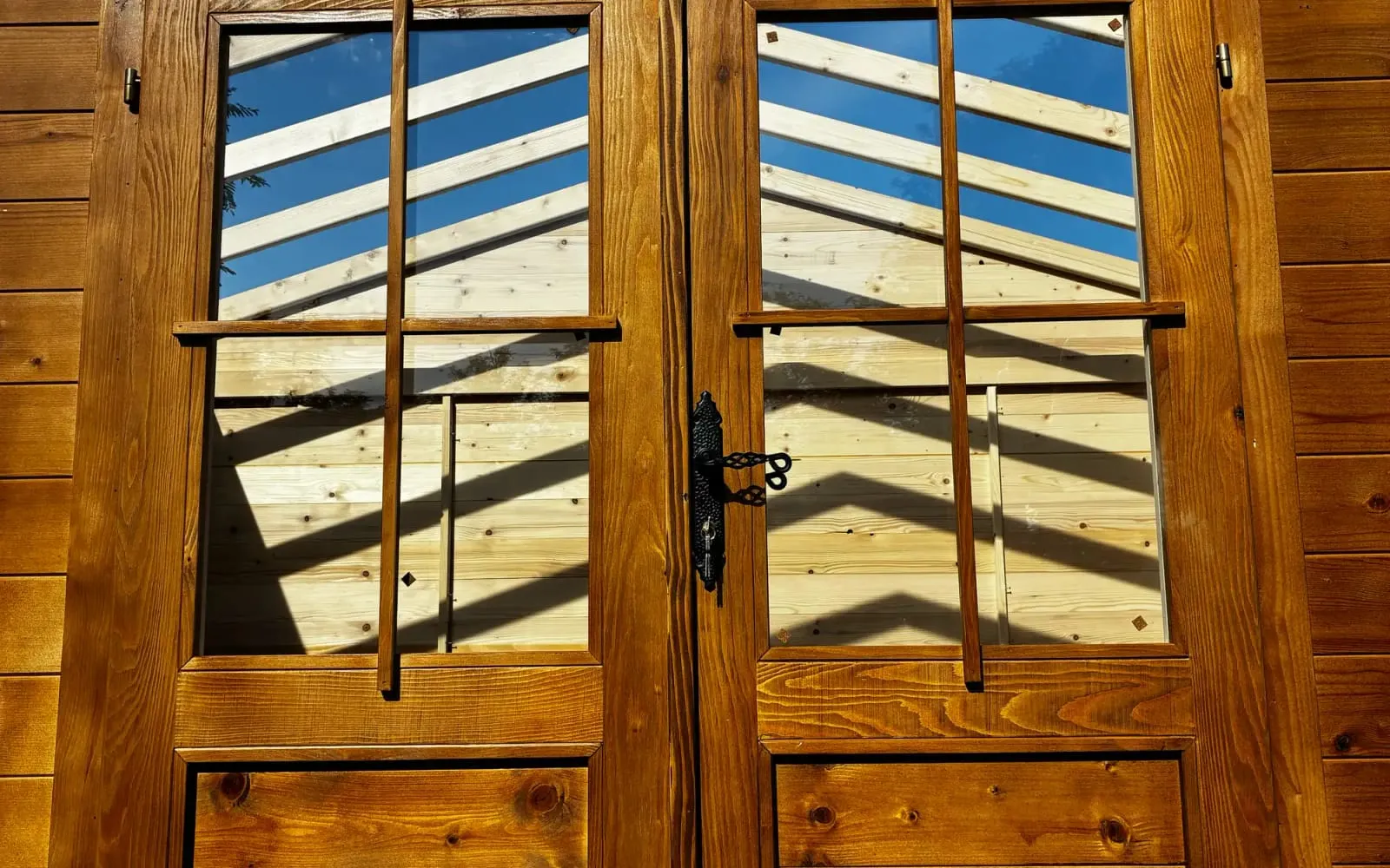 Detalj uljanih drvenih vrata kućice sa odsjajem neba u staklu