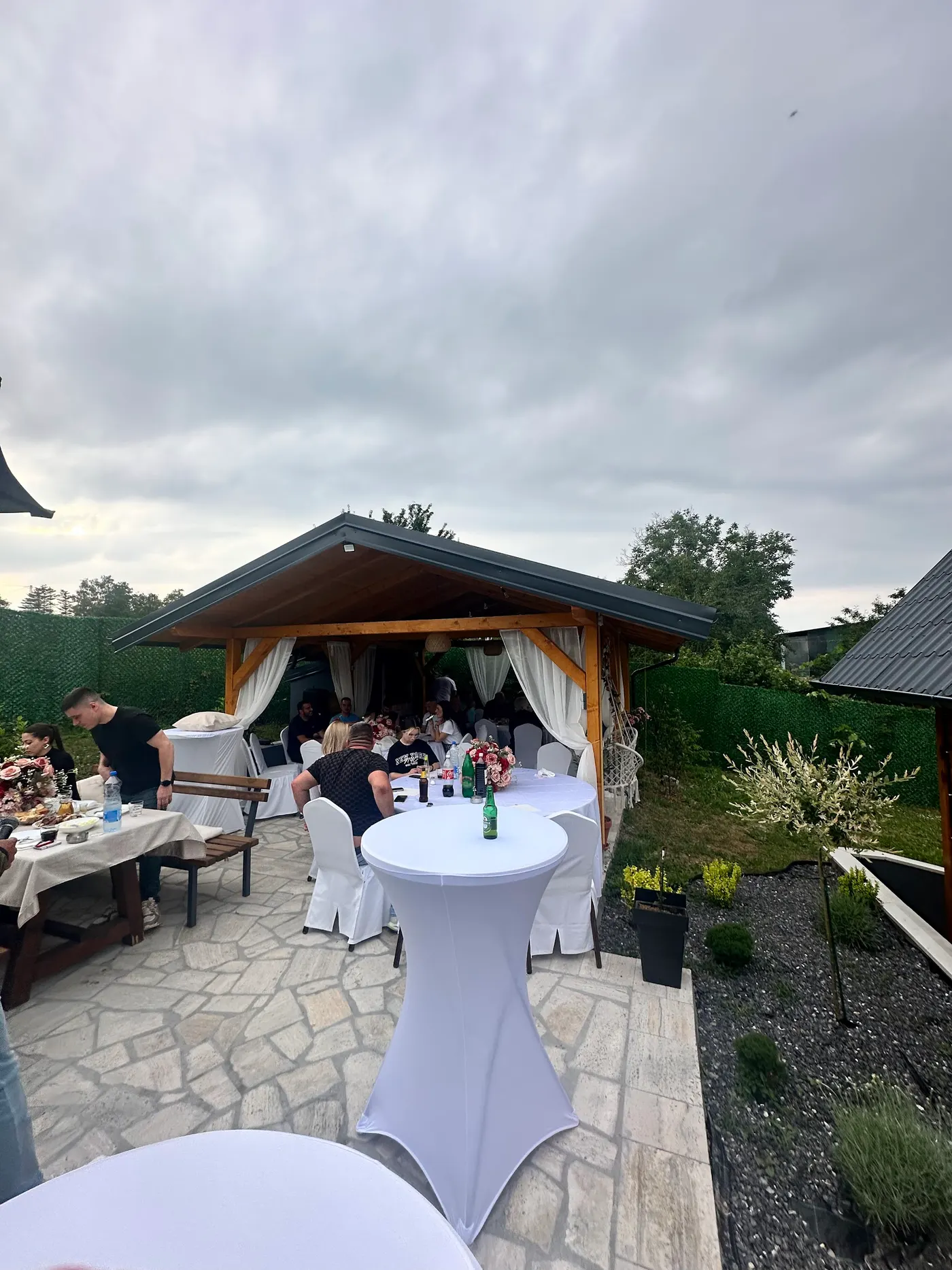 gathering under a wooden canopy in a backyard - Banstol - frame 1