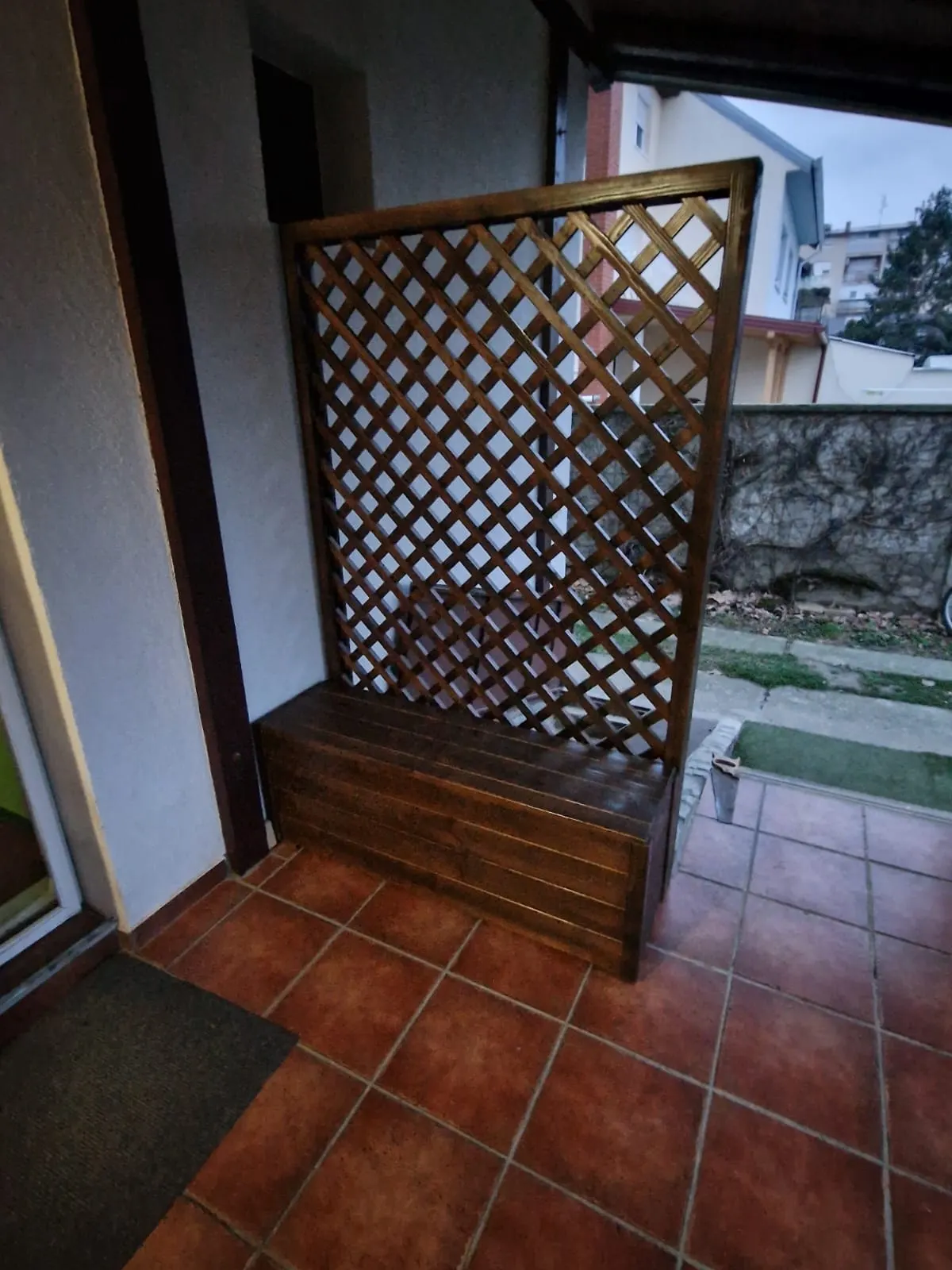 drvena klupa sa sandukom i rešetkasti paravan na terasi - kadar 1